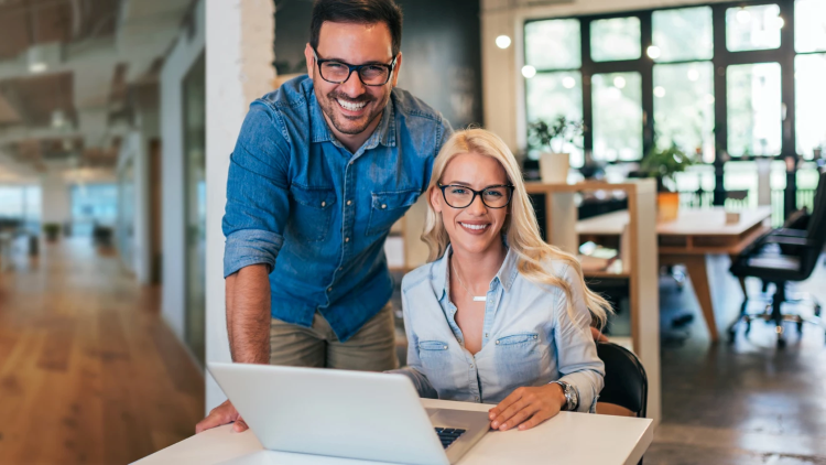 Man and woman standing over a laptop.