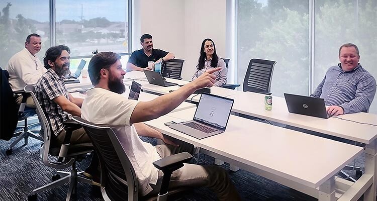 People with laptops sitting around boardroom table