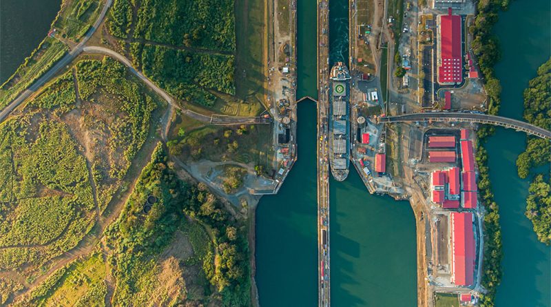 Container ship passing through the Panama Canal with port cranes in the background