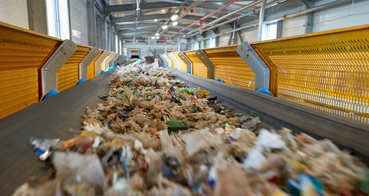a conveyor belt carrying municipal solid waste (MSW) at a waste-to-energy (WtE) facility