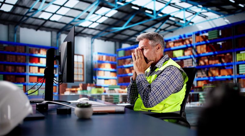 A factory control room with digital warning alerts showing a cyber breach disrupting global supply chains